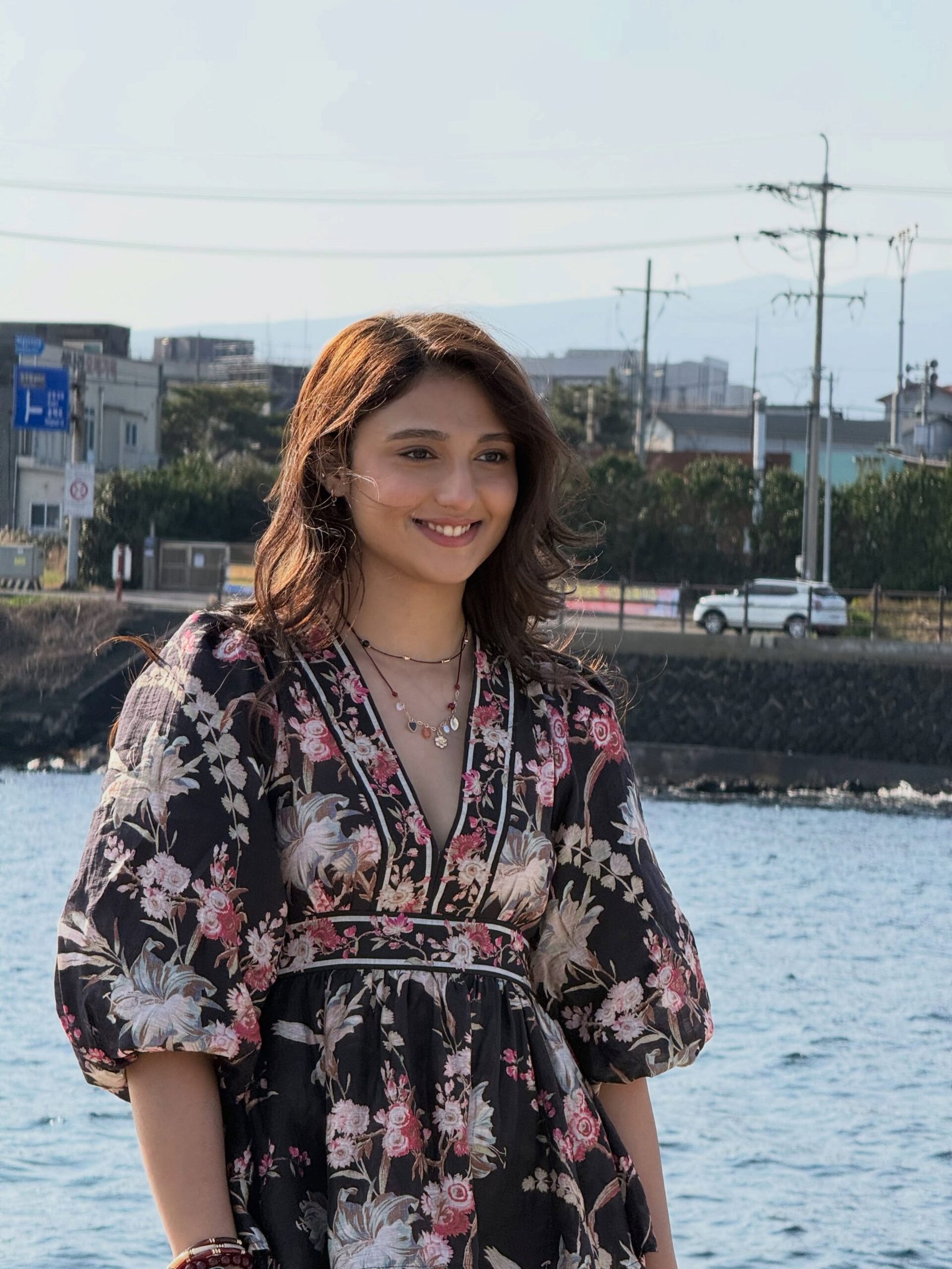 Ritika Nayak posing by the water in a floral dress